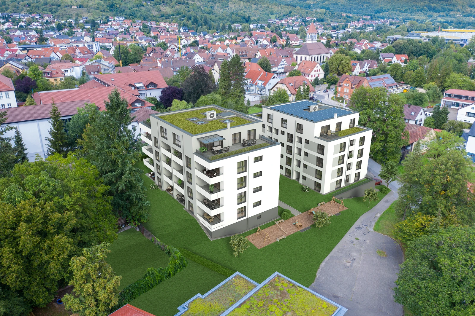 Bronnwiesenweg Rudersberg Luftaufnahme von zwei modernen Wohnbauten mit begrünten Dächern, die von SCHATZ Wohnbau errichtet wurden. Sie liegen inmitten von Bäumen und Grünflächen in einem Wohnviertel mit Einfamilienhäusern und einer nahegelegenen Straße – ein idealer Standort für alle, die eine Wohnung von einem erfahrenen Bauträger erwerben möchten.